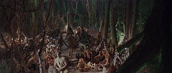 Movie still from “Dr. Who and the Daleks” (1965), directed by Gordon Flemyng – A group of people sitting in the woods; Extreme Wide shot, High angle