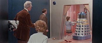 Movie still from “Dr. Who and the Daleks” (1965), directed by Gordon Flemyng – A group of people standing in front of a pink door; Wide shot, High angle