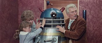 Movie still from “Dr. Who and the Daleks” (1965), directed by Gordon Flemyng – A group of people standing next to a dalek; Medium shot, High angle