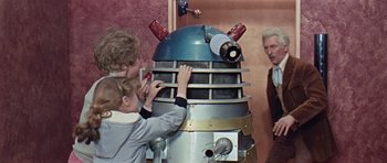 Movie still from “Dr. Who and the Daleks” (1965), directed by Gordon Flemyng – Two children and an older man work on a dalek; Medium shot, Low angle