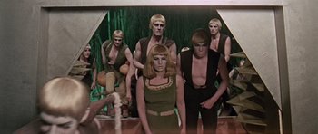 Movie still from “Dr. Who and the Daleks” (1965), directed by Gordon Flemyng – A group of men and a woman standing next to each other; Medium shot, High angle