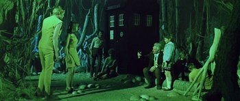Movie still from “Dr. Who and the Daleks” (1965), directed by Gordon Flemyng – A group of people standing in front of a door; Wide shot, Low angle