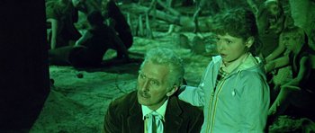 Movie still from “Dr. Who and the Daleks” (1965), directed by Gordon Flemyng – An older man and a young boy are sitting next to each other; Medium shot, Over the shoulder angle