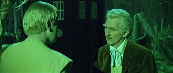 Movie still from “Dr. Who and the Daleks” (1965), directed by Gordon Flemyng – A man in a suit talking to another man in front of a building; Close Up shot, Over the shoulder angle