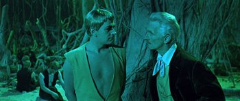 Movie still from “Dr. Who and the Daleks” (1965), directed by Gordon Flemyng – A man and a woman standing next to each other in front of trees; Medium shot, Over the shoulder angle