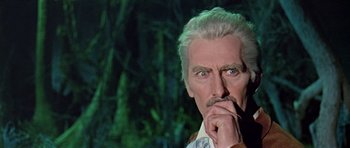 Movie still from “Dr. Who and the Daleks” (1965), directed by Gordon Flemyng – An older man with a mustache and a beard is holding his hand to his face; Close Up shot, Low angle