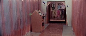 Movie still from “Dr. Who and the Daleks” (1965), directed by Gordon Flemyng – Two women are standing in a room with a wooden cabinet; Wide shot, High angle