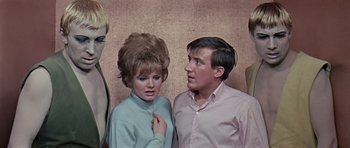 Movie still from “Dr. Who and the Daleks” (1965), directed by Gordon Flemyng – A man and a woman standing next to each other in front of a wall; Medium shot, Low angle