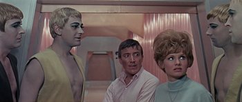 Movie still from “Dr. Who and the Daleks” (1965), directed by Gordon Flemyng – A group of people standing next to each other in a room; Medium shot, Over the shoulder angle