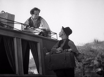 Movie still from “Dracula” (1931), directed by Tod Browning – A man standing on top of a stage holding a suitcase; Medium shot, Low angle