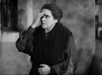 Movie still from “Dracula” (1931), directed by Tod Browning – An older woman is holding her hand up to her forehead; Medium shot, Low angle