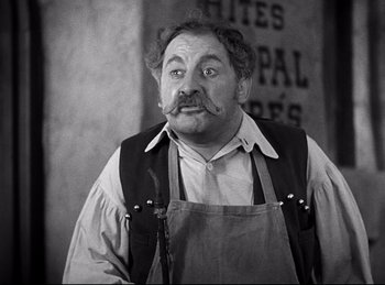 Movie still from “Dracula” (1931), directed by Tod Browning – An old man with a mustache and a beard wearing an apron; Medium shot, High angle