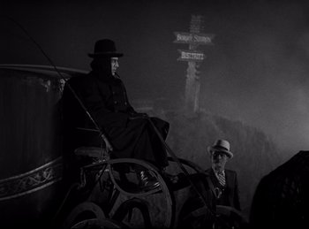 Movie still from “Dracula” (1931), directed by Tod Browning – A man in a black coat and a man in a white hat; Wide shot, Low angle