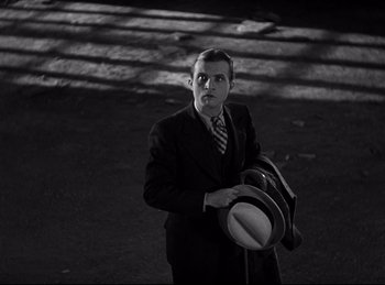 Movie still from “Dracula” (1931), directed by Tod Browning – A black and white photo of a man holding a hat; Medium shot, High angle