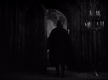 Movie still from “Dracula” (1931), directed by Tod Browning – A man walking through a dark hallway with candles in the background; Wide shot, Low angle
