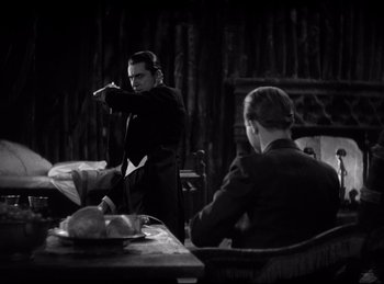 Movie still from “Dracula” (1931), directed by Tod Browning – A man in a suit and tie pointing at a table; Medium shot, Over the shoulder angle