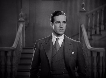 Movie still from “Dracula” (1931), directed by Tod Browning – A man in a suit and tie standing in front of a staircase; Medium shot, Low angle