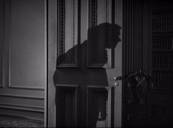 Movie still from “Dracula” (1931), directed by Tod Browning – A black and white photo of a door with a shadow on it; Medium shot, High angle