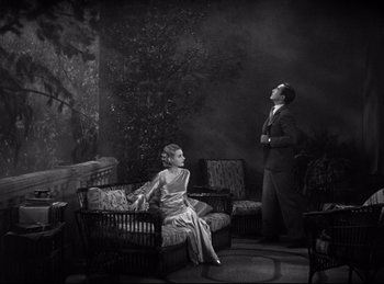 Movie still from “Dracula” (1931), directed by Tod Browning – A man and a woman sitting on a couch in a room; Wide shot, High angle