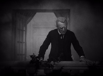 Movie still from “Dracula” (1931), directed by Tod Browning – An old man standing in front of a window; Medium shot, Low angle