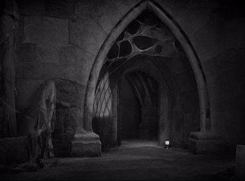 Movie still from “Dracula” (1931), directed by Tod Browning – An empty room with a stone wall and a stone arch; Extreme Wide shot, High angle