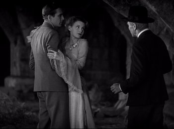 Movie still from “Dracula” (1931), directed by Tod Browning – A man and a woman are standing next to each other in front of an older man; Medium shot, Over the shoulder angle