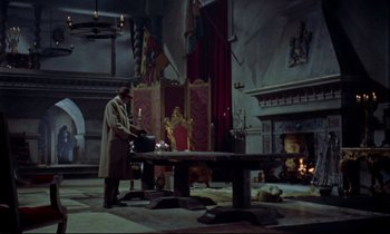 Movie still from “Horror of Dracula” (1958), directed by Terence Fisher – A man standing in front of a table in a living room; Wide shot, High angle