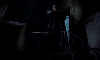 Movie still from “Horror of Dracula” (1958), directed by Terence Fisher – A man in a black robe standing on a staircase; Wide shot, Low angle