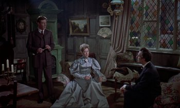 Movie still from “Horror of Dracula” (1958), directed by Terence Fisher – A man and a woman sitting on a chair in a living room; Wide shot, High angle