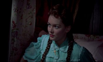 Movie still from “Horror of Dracula” (1958), directed by Terence Fisher – A young woman with braids and a cross necklace; Close Up shot, Over the shoulder angle