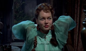 Movie still from “Horror of Dracula” (1958), directed by Terence Fisher – A woman in a green dress holding her hair up; Close Up shot, Over the shoulder angle