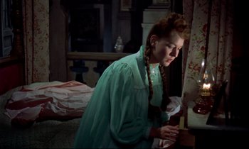 Movie still from “Horror of Dracula” (1958), directed by Terence Fisher – A woman in a green dress standing in front of a window; Medium shot, High angle