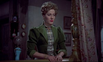 Movie still from “Horror of Dracula” (1958), directed by Terence Fisher – A woman sitting at a table wearing a green jacket; Medium shot, Over the shoulder angle