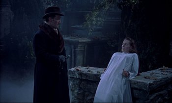 Movie still from “Horror of Dracula” (1958), directed by Terence Fisher – A man and a woman standing next to each other in front of a stone wall; Medium shot, High angle