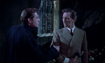 Movie still from “Horror of Dracula” (1958), directed by Terence Fisher – Two men in suits talking to each other in a dark room; Medium shot, Over the shoulder angle