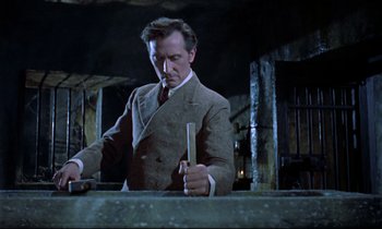 Movie still from “Horror of Dracula” (1958), directed by Terence Fisher – A man in a suit and tie holding a knife; Medium shot, Low angle