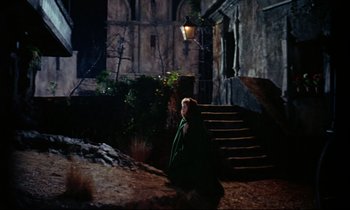 Movie still from “Horror of Dracula” (1958), directed by Terence Fisher – A woman in a green cape walking down a set of stairs; Wide shot, High angle