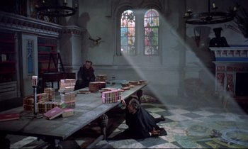 Movie still from “Horror of Dracula” (1958), directed by Terence Fisher – Two people sitting at a table in front of stained glass windows; Wide shot, High angle