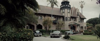 Movie still from “Drag Me to Hell” (2009), directed by Sam Raimi – Cars are parked in front of a large building; Extreme Wide shot, Low angle