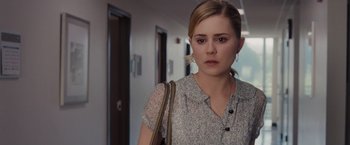 Movie still from “Drag Me to Hell” (2009), directed by Sam Raimi – A young woman in a white shirt is standing in a hallway; Close Up shot, Over the shoulder angle