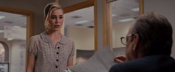 Movie still from “Drag Me to Hell” (2009), directed by Sam Raimi – A woman in a dress is looking at a paper; Medium shot, Over the shoulder angle