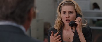 Movie still from “Drag Me to Hell” (2009), directed by Sam Raimi – A woman is talking into a microphone while wearing a headband; Close Up shot, Over the shoulder angle