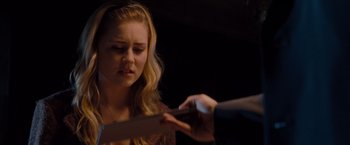 Movie still from “Drag Me to Hell” (2009), directed by Sam Raimi – A woman looking down at a person holding a piece of paper in front of her face; Close Up shot, Over the shoulder angle