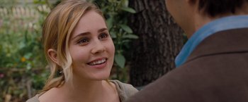 Movie still from “Drag Me to Hell” (2009), directed by Sam Raimi – A young woman smiles at the camera while holding a camera; Close Up shot, Over the shoulder angle