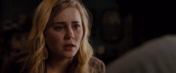 Movie still from “Drag Me to Hell” (2009), directed by Sam Raimi – A young blonde haired woman looking sad with her eyes wide open; Close Up shot, Over the shoulder angle