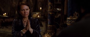 Movie still from “Drag Me to Hell” (2009), directed by Sam Raimi – A woman claps her hands in front of candles; Close Up shot, Over the shoulder angle