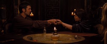 Movie still from “Drag Me to Hell” (2009), directed by Sam Raimi – A man and a woman holding hands over a candle; Medium shot, High angle