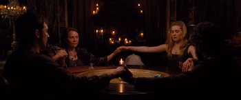 Movie still from “Drag Me to Hell” (2009), directed by Sam Raimi – Two people sitting at a table holding hands; Medium shot, High angle