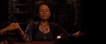 Movie still from “Drag Me to Hell” (2009), directed by Sam Raimi – A woman sitting at a table with her eyes closed; Medium shot, High angle