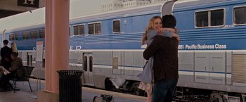 Movie still from “Drag Me to Hell” (2009), directed by Sam Raimi – A man and a woman hugging in front of a train; Wide shot, Over the shoulder angle